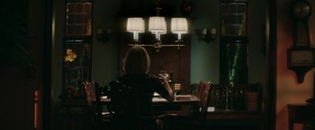 Movie still from “The Sea of Trees” (2015), directed by Gus Van Sant – A woman sitting at a table in front of a lamp; Medium shot, Over the shoulder angle