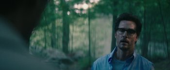 Movie still from “The Sea of Trees” (2015), directed by Gus Van Sant – A man in a blue shirt is standing in the woods; Close Up shot, Over the shoulder angle