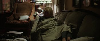 Movie still from “The Sea of Trees” (2015), directed by Gus Van Sant – A woman sitting on a couch wrapped in a blanket; Wide shot, High angle