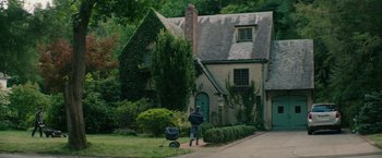 Movie still from “The Sea of Trees” (2015), directed by Gus Van Sant – A man is standing in front of a house with a wheelbarrow; Wide shot, High angle