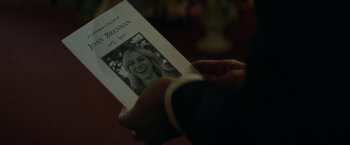 Movie still from “The Sea of Trees” (2015), directed by Gus Van Sant – A person holding a book with a picture of a woman on it; Extreme Close Up shot, Over the shoulder angle