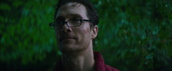 Movie still from “The Sea of Trees” (2015), directed by Gus Van Sant – A person wearing glasses with trees in the background; Close Up shot, Low angle