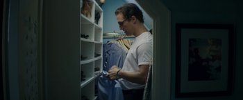 Movie still from “The Sea of Trees” (2015), directed by Gus Van Sant – A man in a white t - shirt is in a walk in closet; Medium shot, Low angle