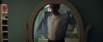 Movie still from “The Sea of Trees” (2015), directed by Gus Van Sant – A man in a mirror holding a blue shirt; Medium shot, Low angle