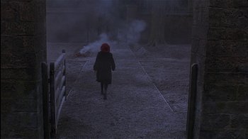 Movie still from “The Secret Garden” (1993), directed by Agnieszka Holland – A woman in a red hat walking down a road; Wide shot, High angle