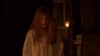 Movie still from “The Secret Garden” (1993), directed by Agnieszka Holland – A woman in a white shirt is standing in a dark room; Close Up shot, Over the shoulder angle