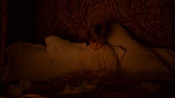 Movie still from “The Secret Garden” (1993), directed by Agnieszka Holland – A person in a bed looking at a cell phone; Medium shot, High angle