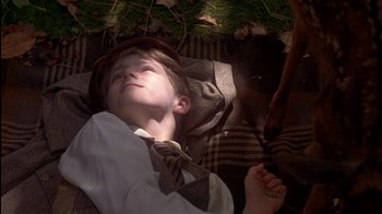 Movie still from “The Secret Garden” (1993), directed by Agnieszka Holland – A young boy laying on the ground in a tie; Medium shot, High angle