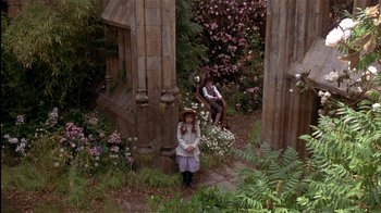 Movie still from “The Secret Garden” (1993), directed by Agnieszka Holland – Two people sitting on pillars in a garden; Wide shot, High angle
