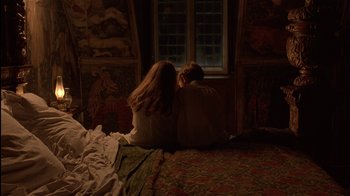 Movie still from “The Secret Garden” (1993), directed by Agnieszka Holland – Two people sitting on a bed in front of a window; Wide shot, Overhead angle