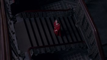 Movie still from “The Secret Garden” (1993), directed by Agnieszka Holland – A woman in a red robe sitting at the top of a set of stairs; Extreme Wide shot, Overhead angle