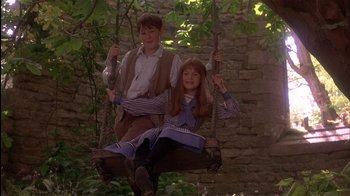 Movie still from “The Secret Garden” (1993), directed by Agnieszka Holland – A boy and a girl are sitting on a swing; Medium shot, Low angle