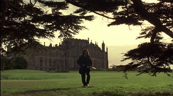 A woman standing in a field near a large building