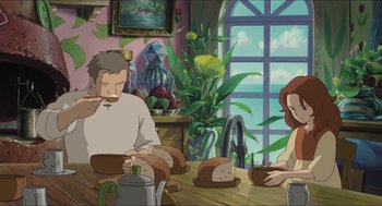 Movie still from “The Secret World of Arrietty” (2010), directed by Hiromasa Yonebayashi – A man and a woman sitting at a table with a loaf of bread in front of them; Wide shot, High angle