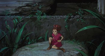 Movie still from “The Secret World of Arrietty” (2010), directed by Hiromasa Yonebayashi – A girl is sitting on the ground holding a yellow object; Wide shot, High angle