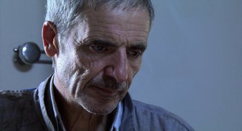 Movie still from “The Secret of the Grain” (2007), directed by Abdellatif Kechiche – An older man with grey hair looking down; Close Up shot, Low angle