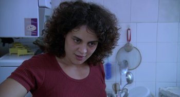Movie still from “The Secret of the Grain” (2007), directed by Abdellatif Kechiche – A woman with curly hair standing in a kitchen; Close Up shot, Over the shoulder angle