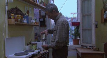Movie still from “The Secret of the Grain” (2007), directed by Abdellatif Kechiche – An older man is cooking in the kitchen; Medium shot, Low angle