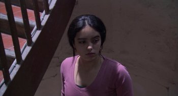 Movie still from “The Secret of the Grain” (2007), directed by Abdellatif Kechiche – A woman in a purple shirt is standing in front of a staircase; Close Up shot, High angle