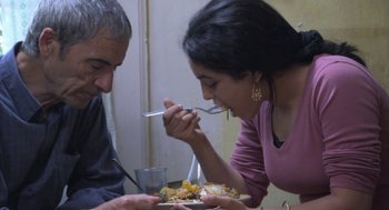 Movie still from “The Secret of the Grain” (2007), directed by Abdellatif Kechiche – A man and a woman are eating food together; Medium shot, Over the shoulder angle
