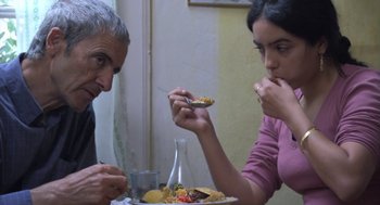 Movie still from “The Secret of the Grain” (2007), directed by Abdellatif Kechiche – A man and a woman are eating a meal together; Medium shot, Over the shoulder angle