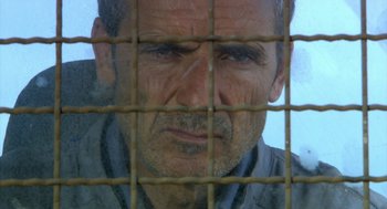 Movie still from “The Secret of the Grain” (2007), directed by Abdellatif Kechiche – A person behind a fence; Close Up shot, Low angle