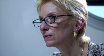 Movie still from “The Secret of the Grain” (2007), directed by Abdellatif Kechiche – A person wearing glasses and looking to the side; Close Up shot, Over the shoulder angle