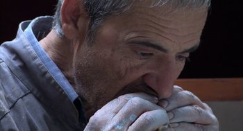 Movie still from “The Secret of the Grain” (2007), directed by Abdellatif Kechiche – An older man is eating a piece of food; Extreme Close Up shot, Overhead angle