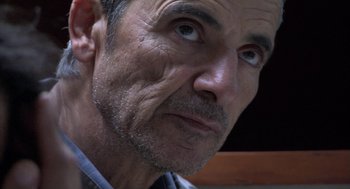 Movie still from “The Secret of the Grain” (2007), directed by Abdellatif Kechiche – An older man looking at the camera while wearing a blue shirt; Close Up shot, Over the shoulder angle