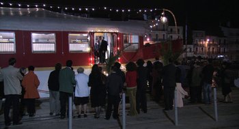 Movie still from “The Secret of the Grain” (2007), directed by Abdellatif Kechiche – A group of people standing on the side of a red train; Extreme Wide shot, High angle