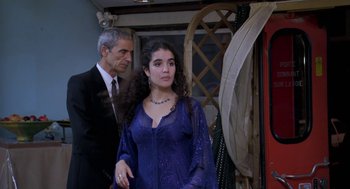 Movie still from “The Secret of the Grain” (2007), directed by Abdellatif Kechiche – A man standing next to a woman in a purple dress; Medium shot, Over the shoulder angle