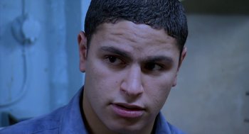 Movie still from “The Secret of the Grain” (2007), directed by Abdellatif Kechiche – A person wearing a blue shirt; Close Up shot, High angle