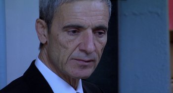 Movie still from “The Secret of the Grain” (2007), directed by Abdellatif Kechiche – An older man wearing a suit and tie looking sad; Close Up shot, Over the shoulder angle