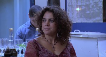 Movie still from “The Secret of the Grain” (2007), directed by Abdellatif Kechiche – A person with curly hair wearing a necklace; Close Up shot, Over the shoulder angle