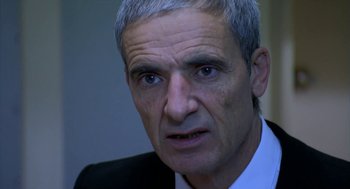 Movie still from “The Secret of the Grain” (2007), directed by Abdellatif Kechiche – An older man in a white shirt and a black suit; Close Up shot, Over the shoulder angle