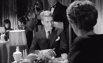 Movie still from “The Servant” (1963), directed by Joseph Losey – A black and white photo of a man and a woman at a dinner table; Medium shot, Over the shoulder angle