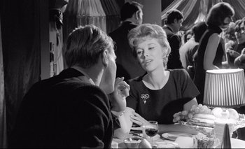 Movie still from “The Servant” (1963), directed by Joseph Losey – Two people sitting at a table with a glass of red wine; Medium shot, Over the shoulder angle