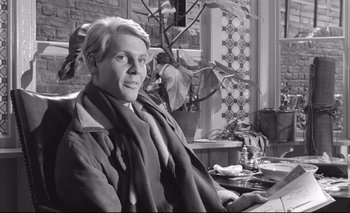 Movie still from “The Servant” (1963), directed by Joseph Losey – Black and white photograph of a man sitting at a table; Close Up shot, Low angle