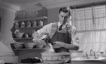 A man in an apron is stirring something in a bowl