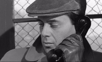 Movie still from “The Servant” (1963), directed by Joseph Losey – A black and white photo of a man talking on a phone; Close Up shot, Overhead angle