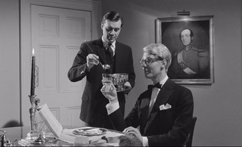 Movie still from “The Servant” (1963), directed by Joseph Losey – Two men in suits are eating at a dinner table; Medium shot, Low angle