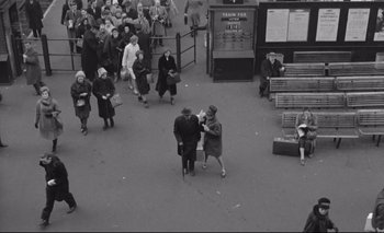 Movie still from “The Servant” (1963), directed by Joseph Losey – An old black and white photo of a crowd of people; Extreme Wide shot, Overhead angle