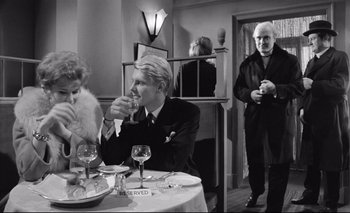 Movie still from “The Servant” (1963), directed by Joseph Losey – A man and a woman sitting at a dinner table; Medium shot, Over the shoulder angle