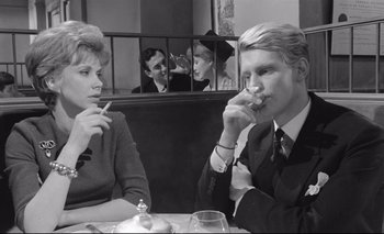 Movie still from “The Servant” (1963), directed by Joseph Losey – A man and a woman sitting at a table in front of another man; Medium shot, Over the shoulder angle