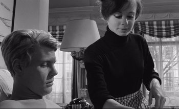 Movie still from “The Servant” (1963), directed by Joseph Losey – A man and a woman are standing in front of a lamp; Close Up shot, Low angle