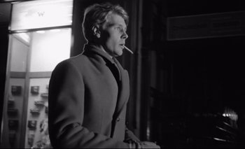 Movie still from “The Servant” (1963), directed by Joseph Losey – A black and white photo of a man smoking a cigarette; Close Up shot, Low angle