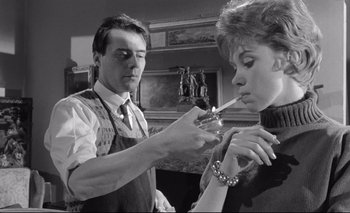 Movie still from “The Servant” (1963), directed by Joseph Losey – A man and a woman are smoking a cigarette together; Medium shot, Low angle