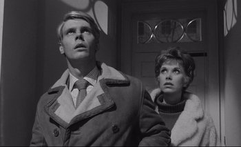 Movie still from “The Servant” (1963), directed by Joseph Losey – A man and a woman standing next to each other in front of a door; Close Up shot, Low angle