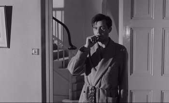 Movie still from “The Servant” (1963), directed by Joseph Losey – A man standing in front of a mirror holding a toothbrush in his mouth; Medium shot, Low angle