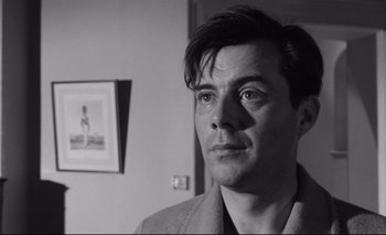 Movie still from “The Servant” (1963), directed by Joseph Losey – Black and white photograph of a man looking at the camera; Close Up shot, Low angle